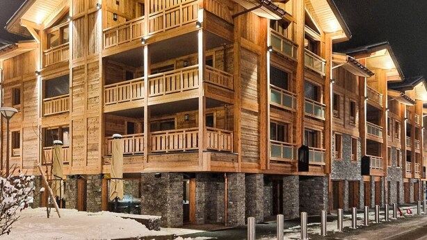 A multi-story wooden building with balconies and large windows, likely a hotel or resort. - Spacious apartment in Les Gets, 4 bedrooms, sauna (Les Gets)