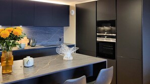 A modern kitchen with dark cabinetry, a marble countertop, and a built-in oven. - Spacious apartment in Les Gets, 4 bedrooms, sauna (Les Gets)