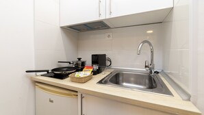 Een kleine keuken met een spoelbak, fornuis en kastjes.