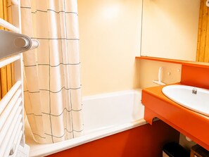 Un baño con bañera, lavamanos blanco y encimera naranja.