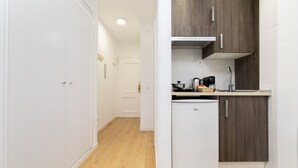 Une cuisine moderne avec des meubles blancs, un réfrigérateur blanc et un plan de travail en bois.