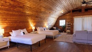Een knus houten blokhut slaapkamer met twee bedden, een bank en een zitje.