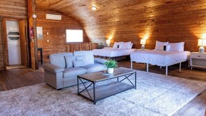 Een knus kamer in chaletstijl met houten plafond, een bank, twee bedden en een salontafel.