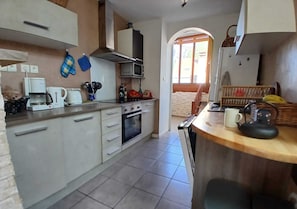 A kitchen with white cabinets, a microwave, a coffee maker, and a wooden countertop.