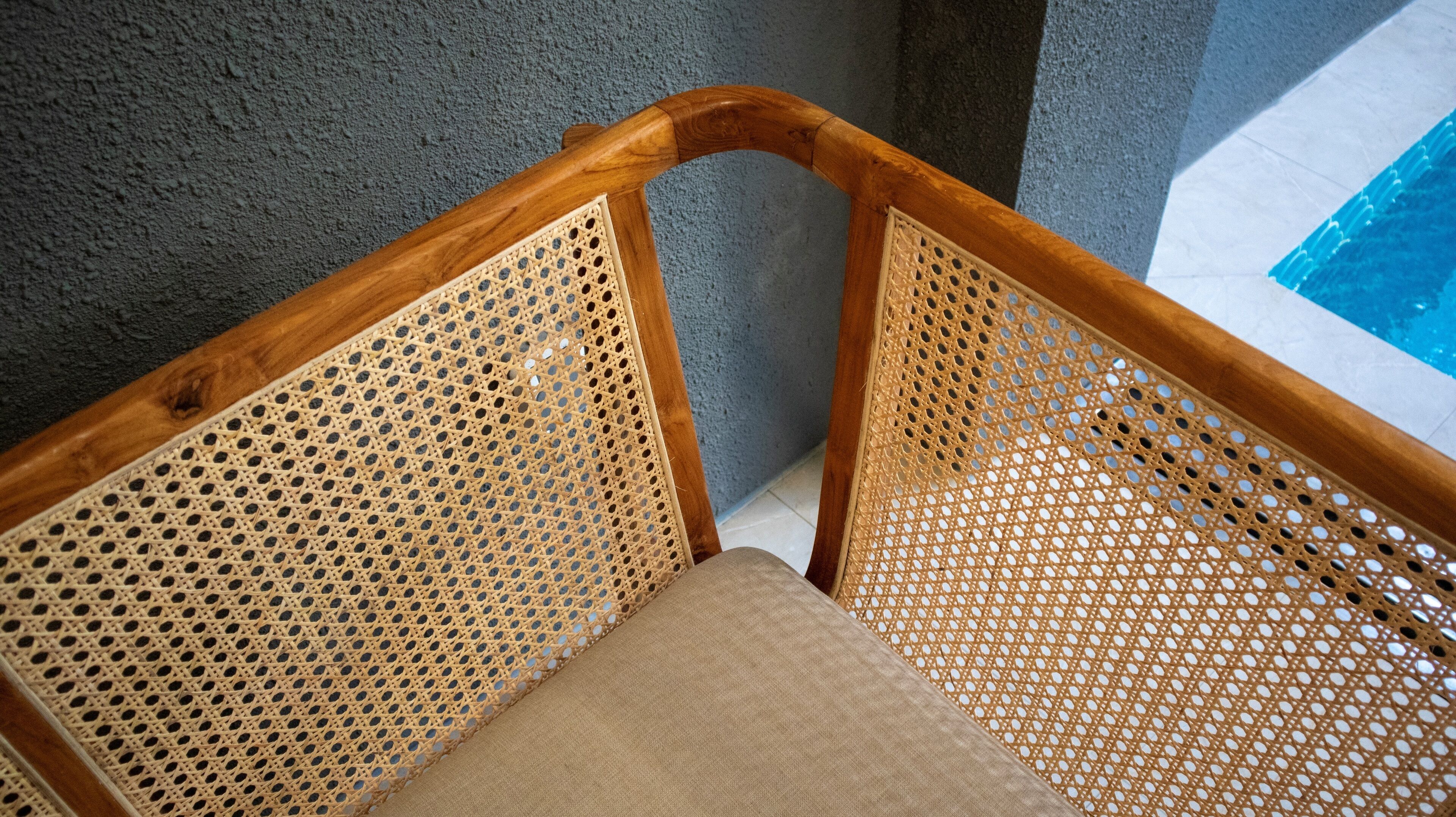 A corner of a room with a wooden chair and a pool.