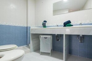 A bathroom with a white sink, blue-tiled walls, a white toilet, and a small white stool. - Villa Gaviota: Beachfront Luxury in Marina del Este - Book Now! (Almuñécar)