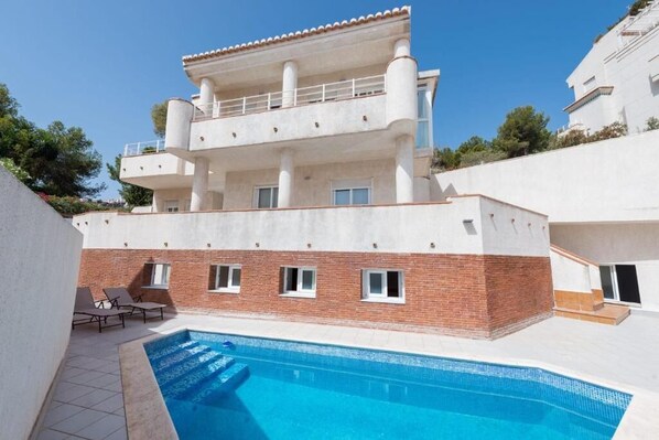 A multi-story building with a swimming pool in the foreground. - Villa Gaviota: Beachfront Luxury in Marina del Este - Book Now! (Almuñécar)