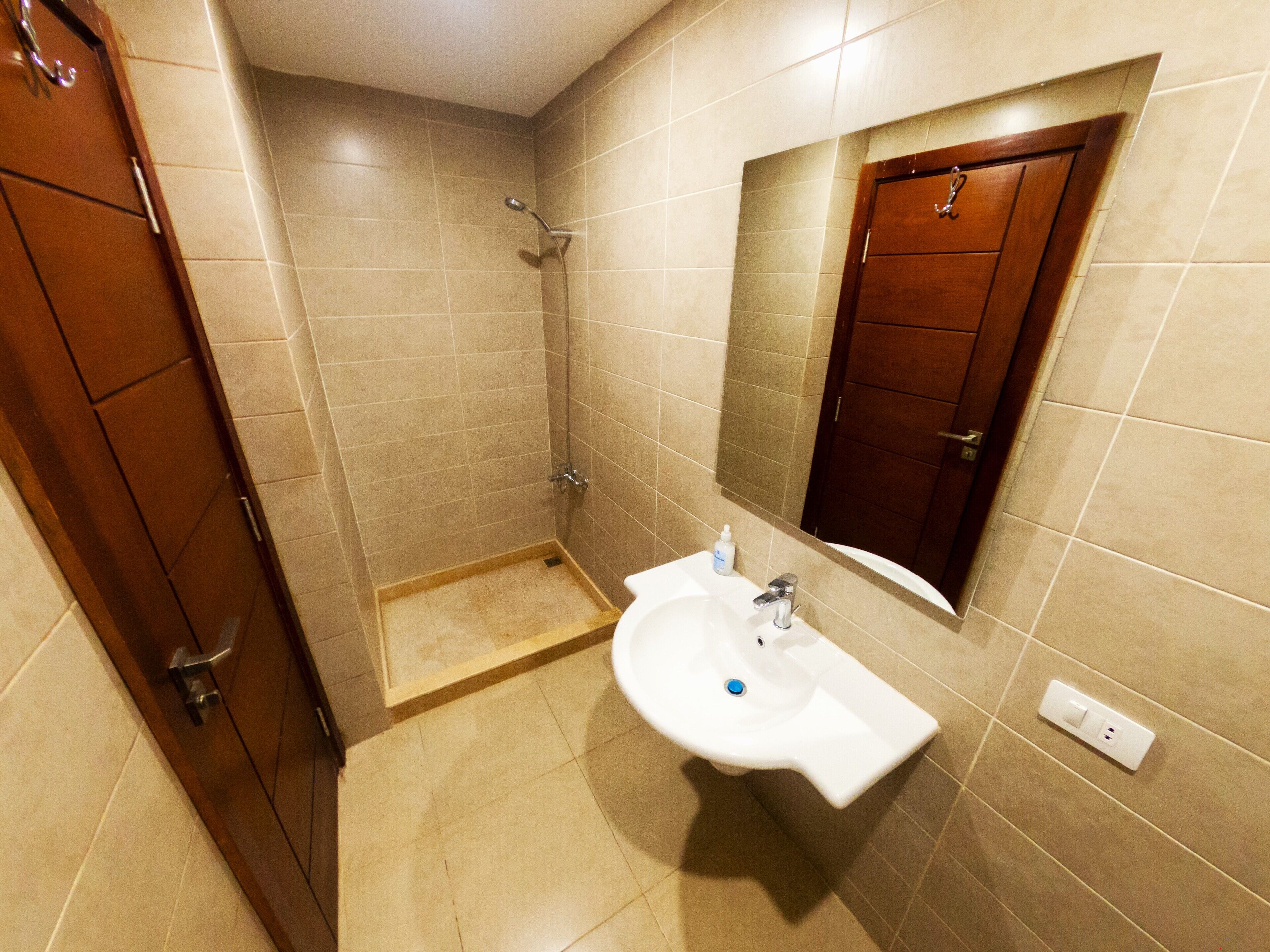 Un baño con ducha, lavamanos y espejo.
