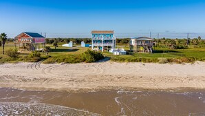 A beachfront property with multiple buildings, including a large two-story house with a balcony and a smaller house with a porch.