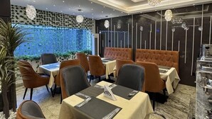 Ein modernes Restaurant mit Tischen, Stühlen, dekorativer Beleuchtung und einer Wand mit Muster.
