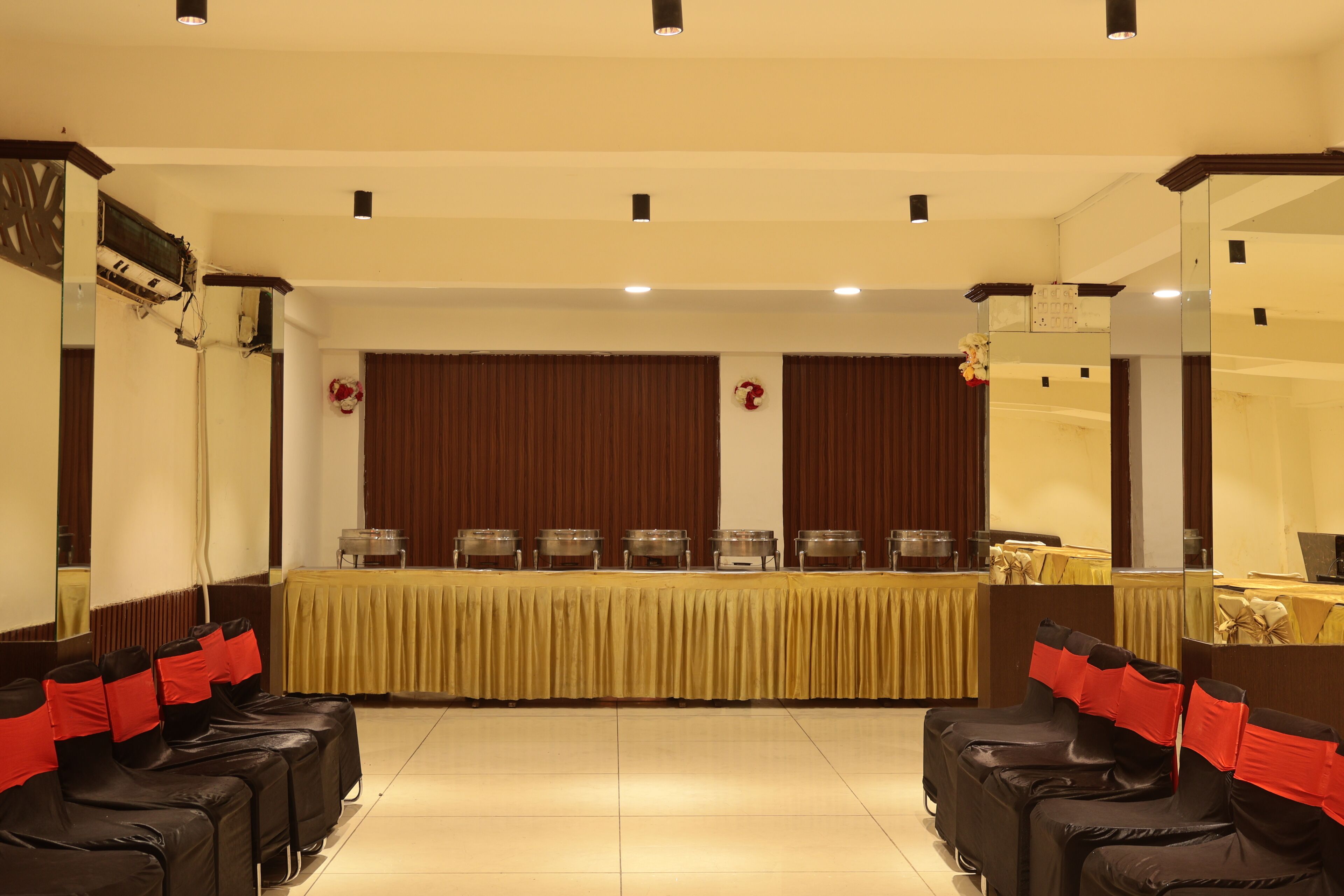 A conference room with a long table, rows of chairs, and a stage with curtains.