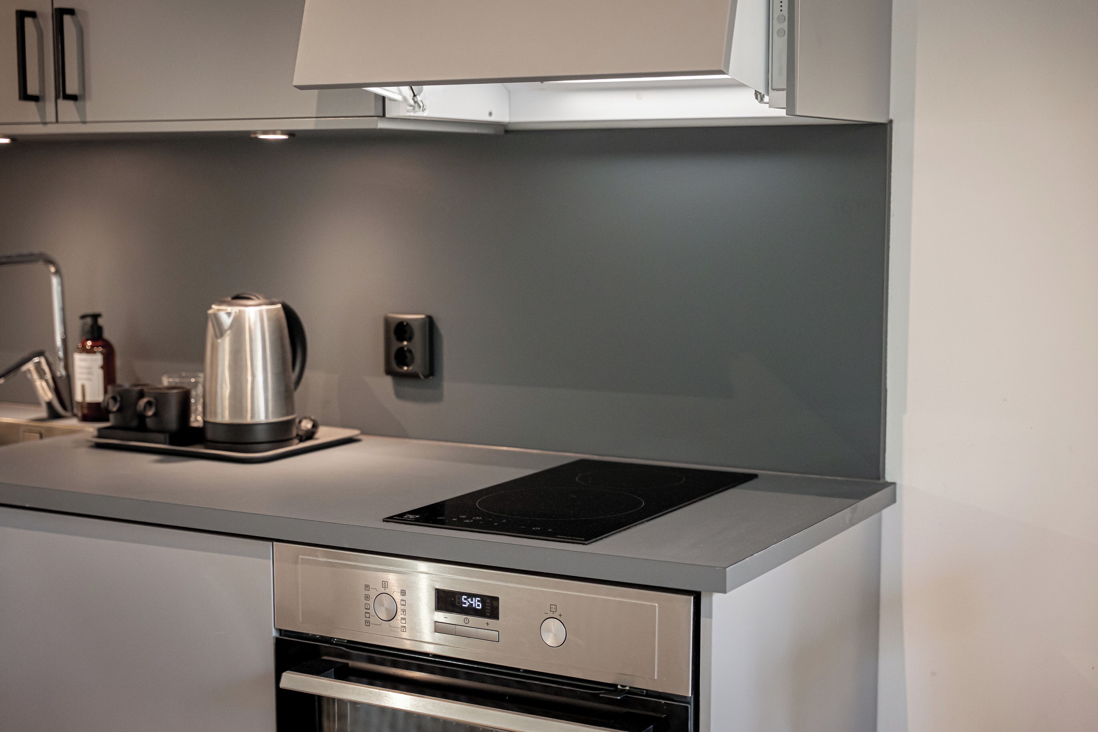 A modern kitchen with a built-in oven, a stovetop, and a coffee maker.