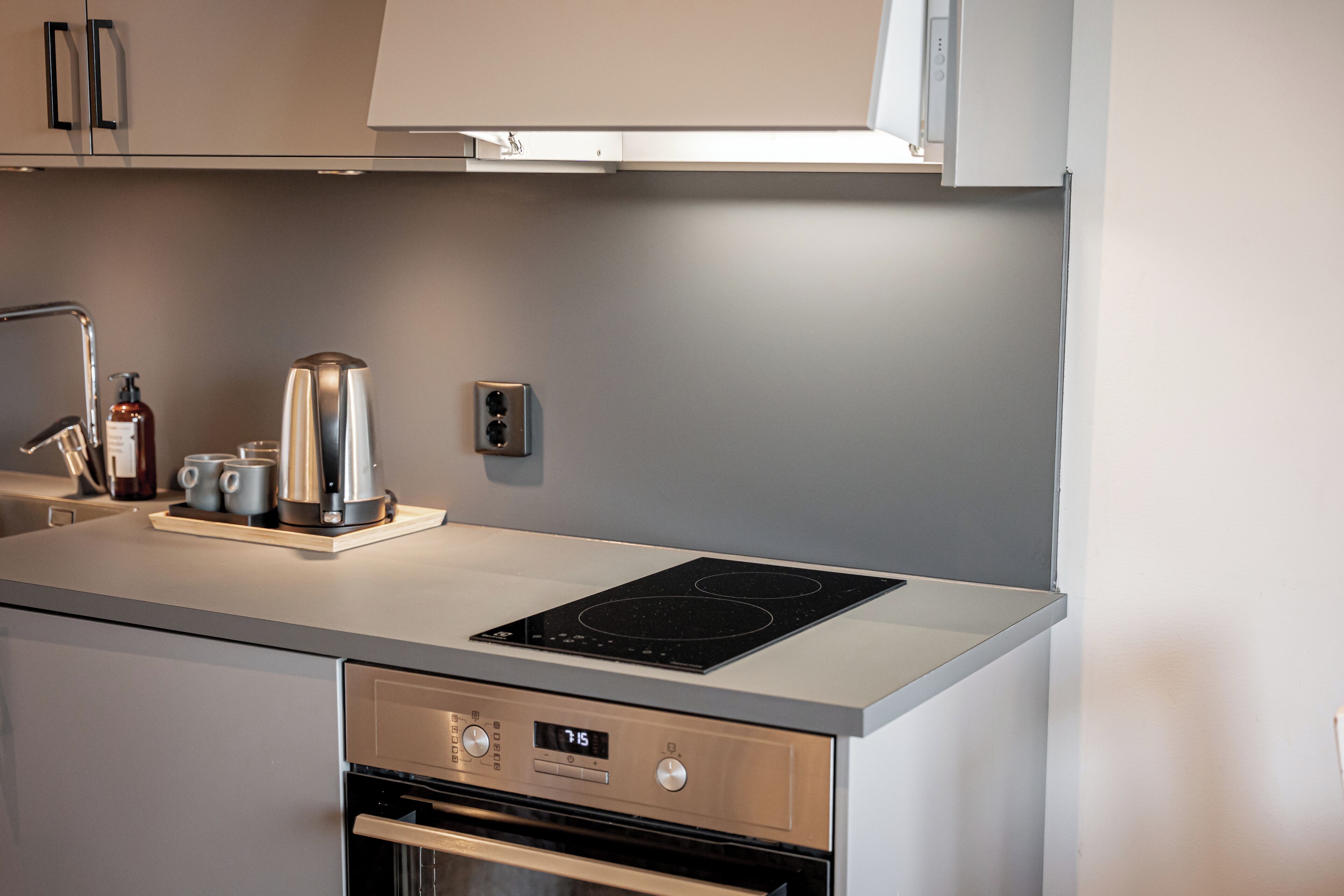 Una cocina moderna con horno integrado, cafetera y tetera sobre la encimera.