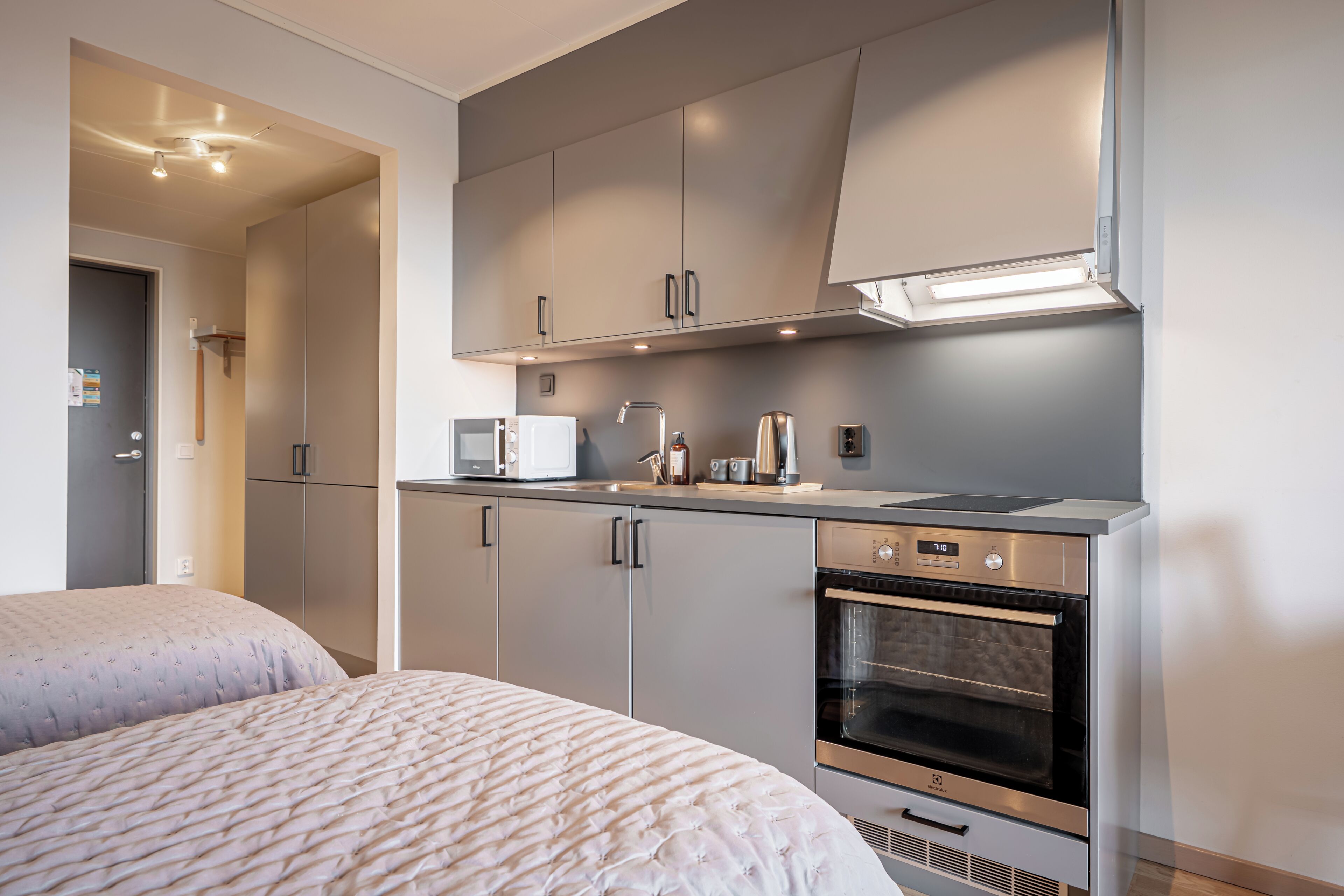 Una cocina compacta con electrodomésticos modernos, microondas, cafetera y horno empotrado.