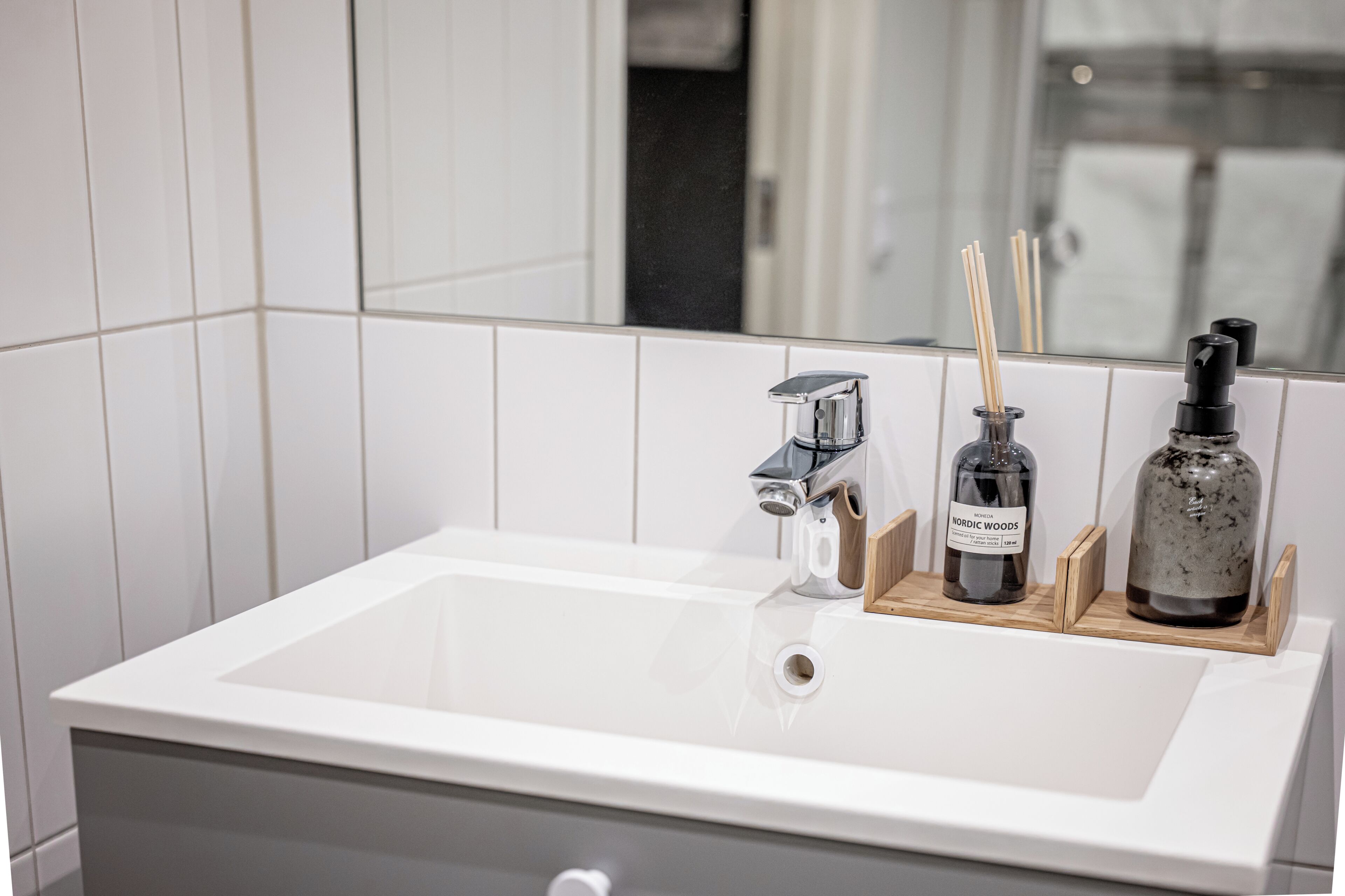 Une salle de bain moderne avec un lavabo blanc, un robinet chromé et un miroir qui reflète la pièce.