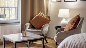 Un salon chaleureux avec un fauteuil gris, une table blanche et une lampe.