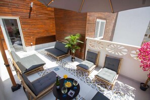 A sunlit outdoor seating area with wooden walls, cushioned chairs, a small table with drinks, and a potted plant. - Art Apartment VII, private terrace (Alicante (Alacant))