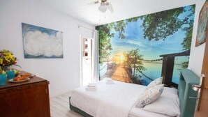 Una camera da letto con un letto, una scrivania con un vaso di fiori e un quadro appeso al muro.