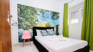 Een slaapkamer met een bed, een muurschildering, een roze stoel en groene gordijnen.