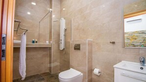 Een badkamer met een douche, toilet, wastafel en een handdoekhouder.