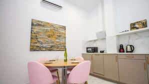 Een moderne keuken met een eethoek, met een marmeren aanrecht, een magnetron, een koffiezetapparaat en een schilderij aan de muur.
