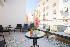 A balcony with a round table, chairs, a sofa, and a potted plant. - Art Apartment V, Three Bedroom Apartment with private terrace (Alicante (Alacant))