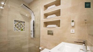 Un baño moderno con ducha de vidrio, inodoro y lavamanos con espejo.