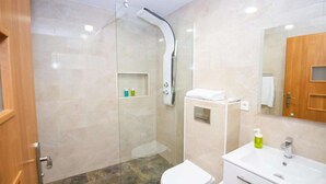 A modern bathroom with a glass-enclosed shower, a white toilet, and a vanity with a mirror.