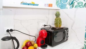 A kitchen with a microwave, a red coffee maker, and a fruit bowl on the counter.