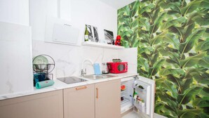 A modern kitchen with a white countertop, a sink, a red microwave, and a refrigerator. - Art Apartment IV, Two-Bedroom Apartment (Alicante (Alacant))