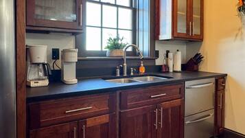 A kitchen with wooden cabinets, a coffee maker, a sink, and a window with a view.