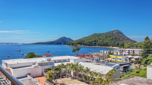 Un pueblo costero con edificios, un cielo azul despejado y barcos en el agua.