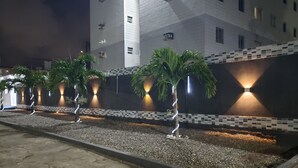 Un edifici amb façana de rajola, palmeres i un passeig pavimentat.