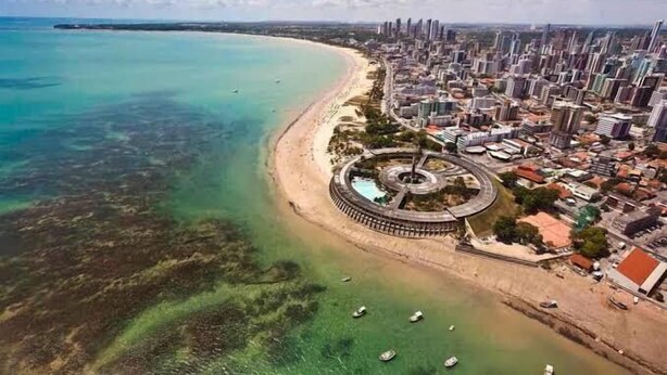 Vista aèria d'una ciutat costanera amb una platja, una rotonda i edificis alts.