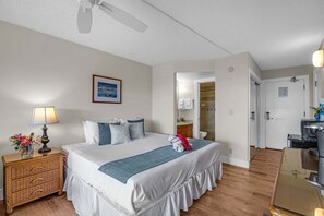 A hotel room with a bed, bedside table, lamp, and a ceiling fan.