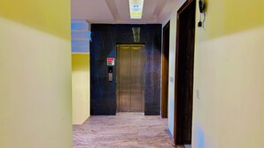 A hallway with a marble floor, a door with a security keypad, and a ceiling light fixture. - Hotel GoodLuck House Near Delhi Airport (New Delhi)