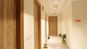 A hallway with wooden doors, a no-smoking sign, and potted plants. - Hotel GoodLuck House Near Delhi Airport (New Delhi)