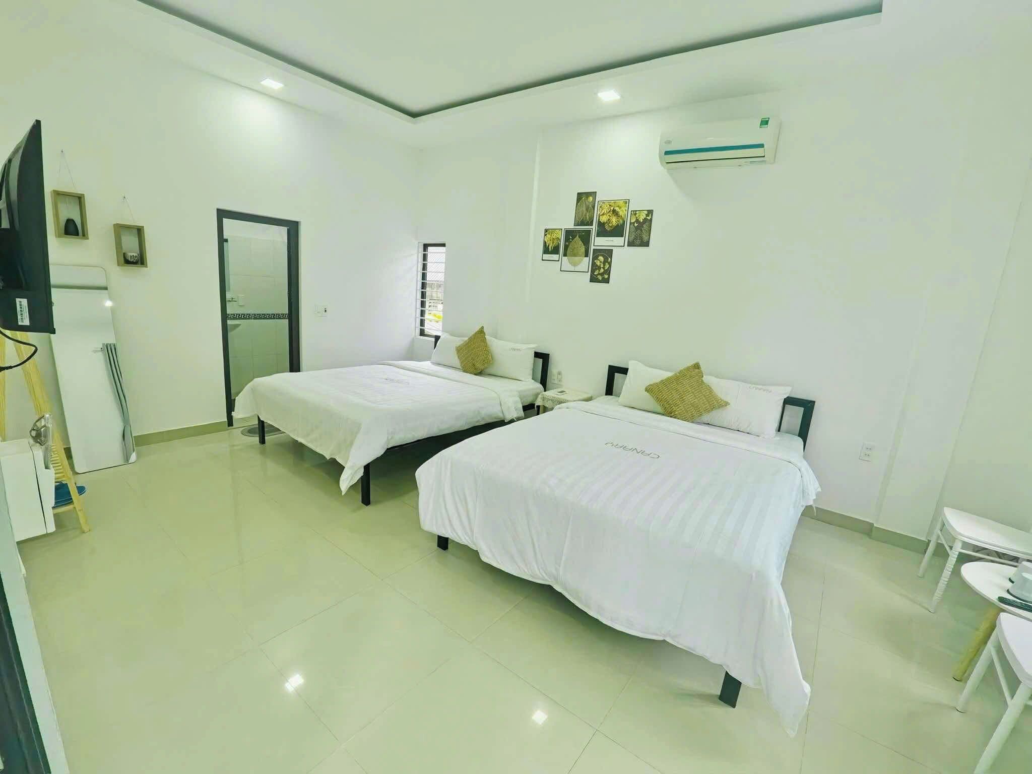 A hotel room with two beds, a small table, and a TV.