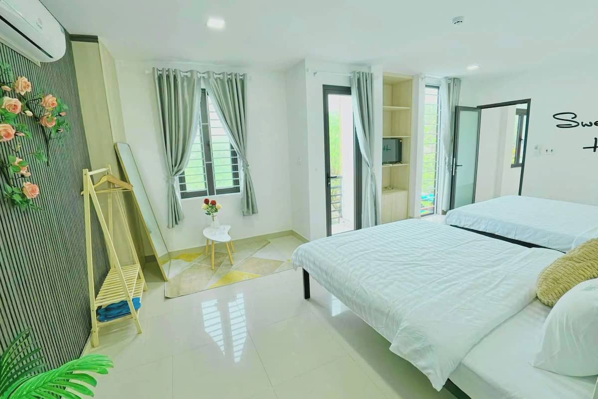 A bedroom with a bed, a small table with a vase of flowers, a wardrobe, and a mirror on the wall.