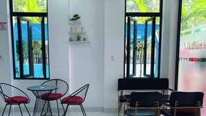 A modern room with large windows, a small table with chairs, and a piano. - TORI HOMESTAY (Hue)