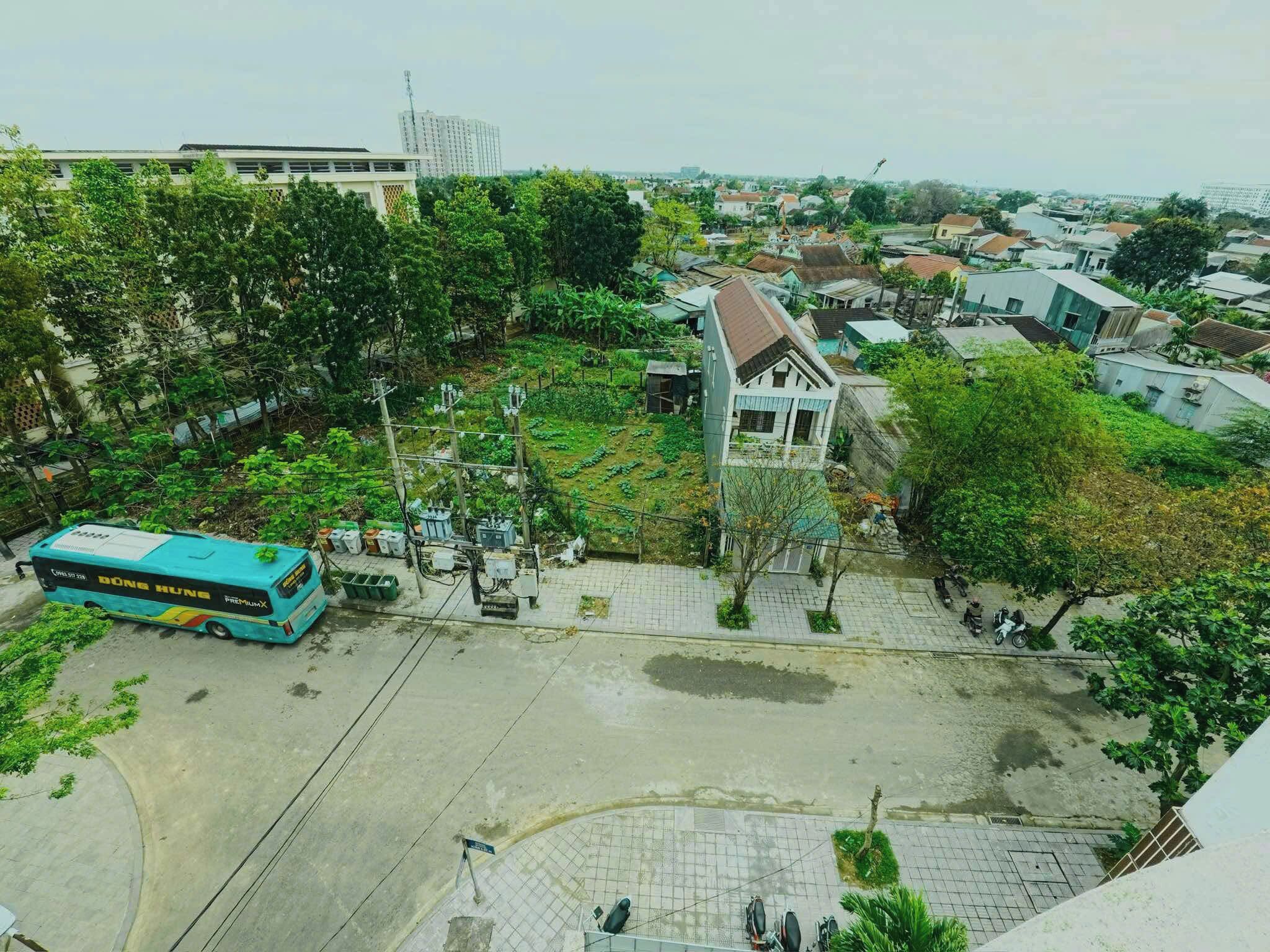 An aerial view of a residential area with a bus, a small building, and a paved area with trees.