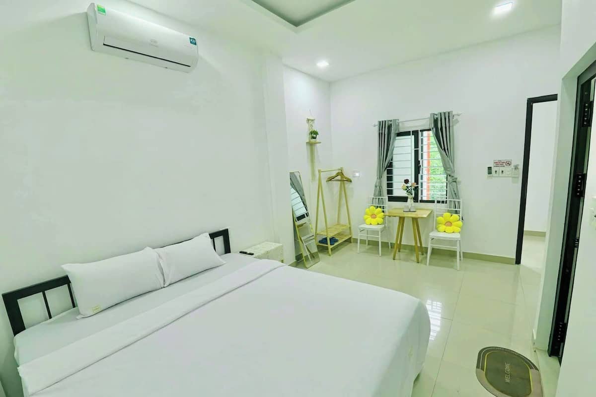 A hotel room with a bed, a small table, chairs, and a window with curtains.
