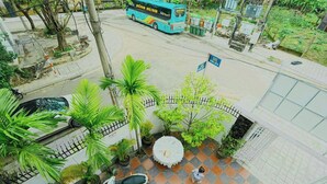 A multi-story building with a rooftop terrace featuring potted plants and a small table. - TORI HOMESTAY (Hue)
