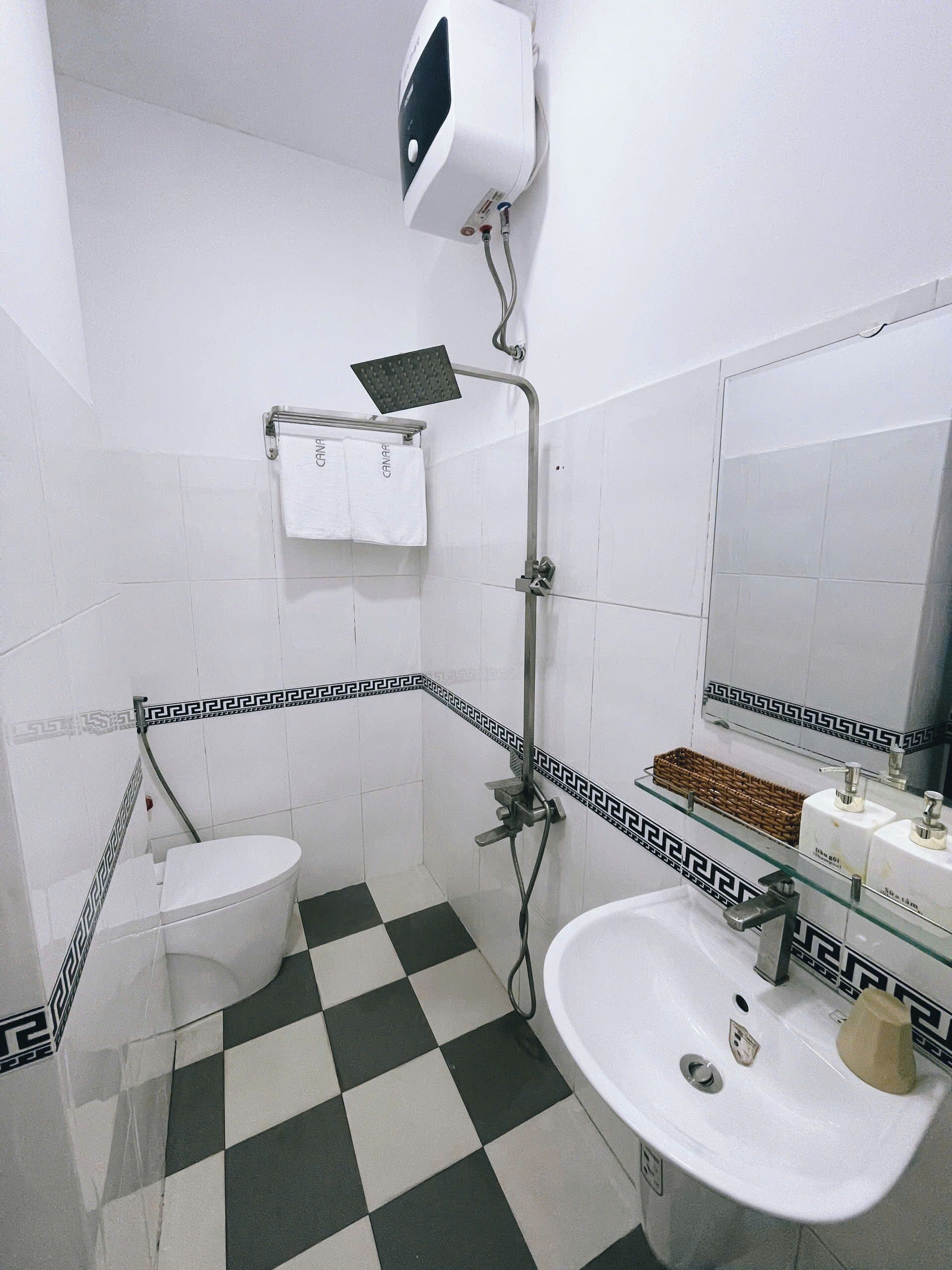 A bathroom with a toilet, a sink, a shower, and a towel rack.