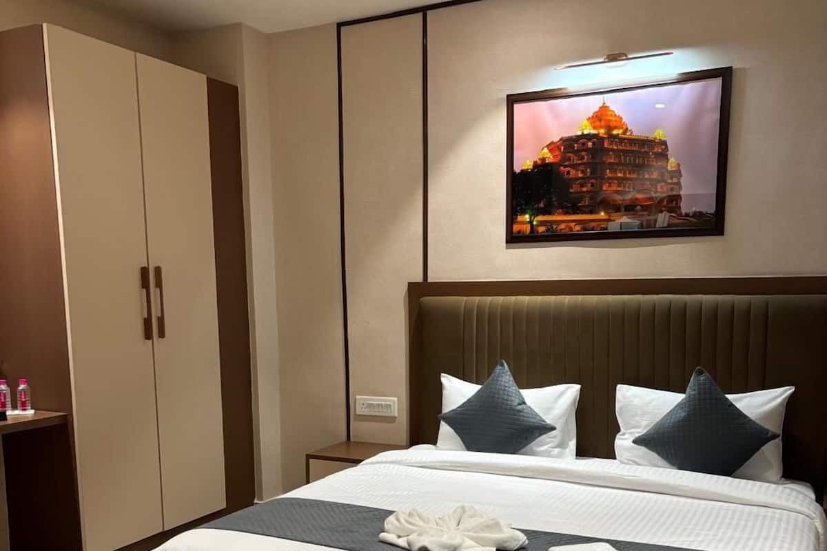A modern hotel room with a large bed, a wardrobe, and a framed picture on the wall.