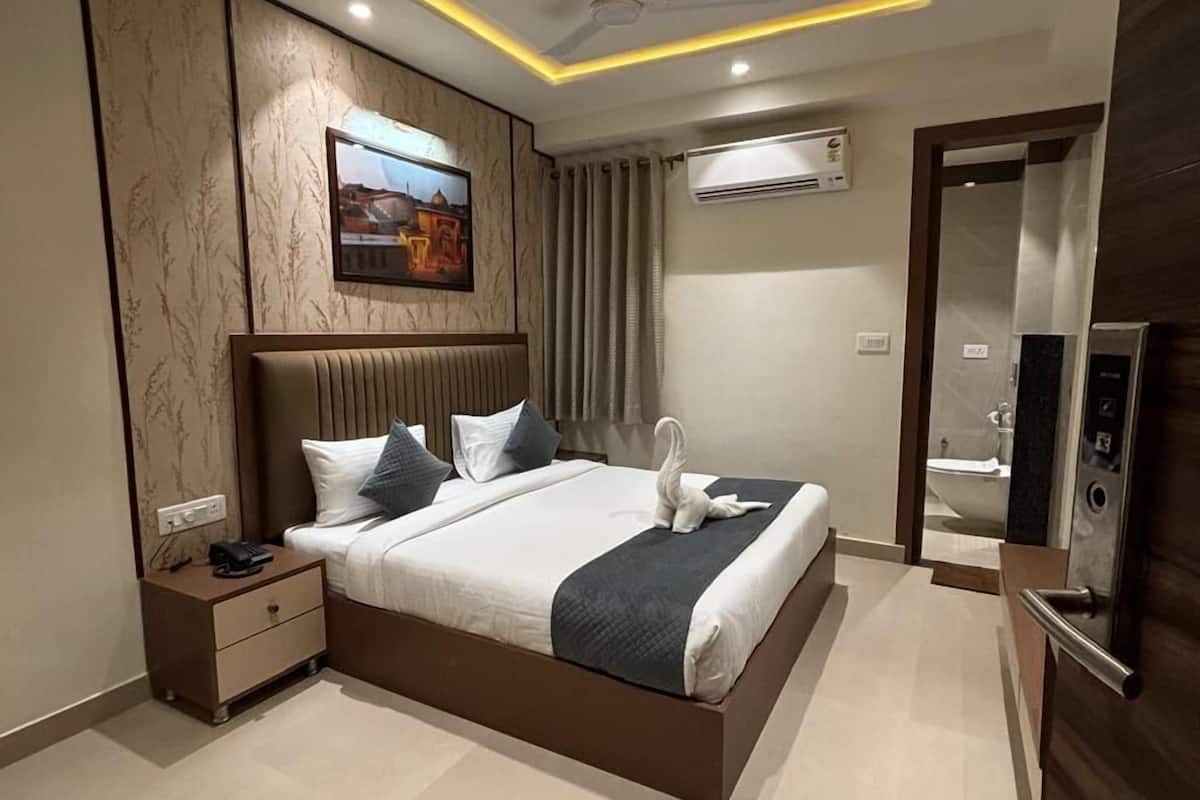 A modern hotel room with a large bed, bedside tables, a ceiling fan, and an air conditioning unit.