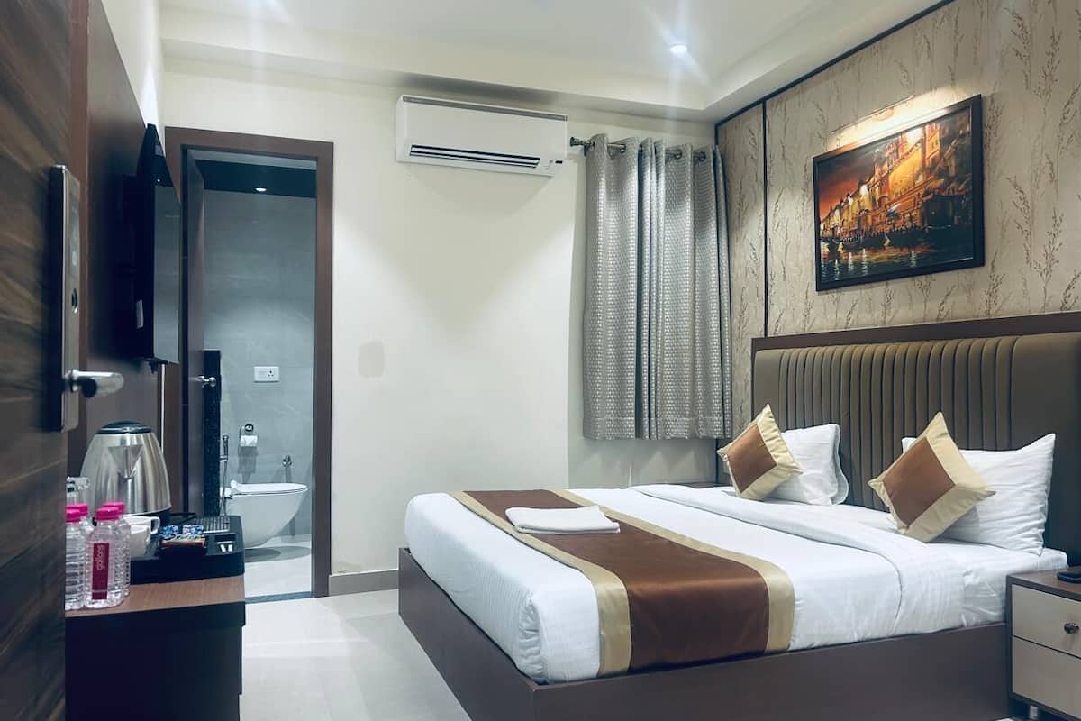 A hotel room with a bed, bedside table, and a painting on the wall.