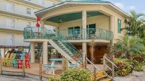 Un hotel de varios pisos con techo curvo, asientos exteriores y zona de piscina.