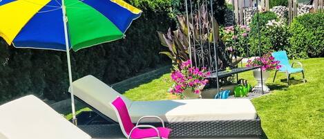 A pool area with lounge chairs and a colorful umbrella.