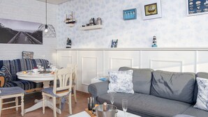 Una sala de estar acogedora con un sofá gris, una mesa de centro blanca y un comedor con un sofá a rayas y una mesita redonda.
